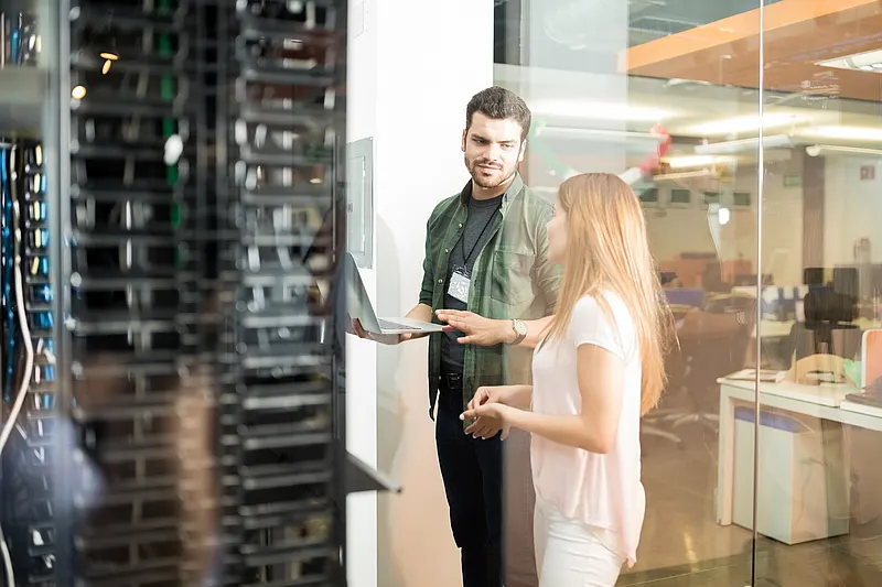 Maßnahmen zur Energieeffizienz von Rechenzentren: Analyse vor Ort anhand präziser Messdaten Techniker und Ingenieur besprechen Maßnahmen zur Energieeffizienz von Rechenzentren außerhalb des Serverraums